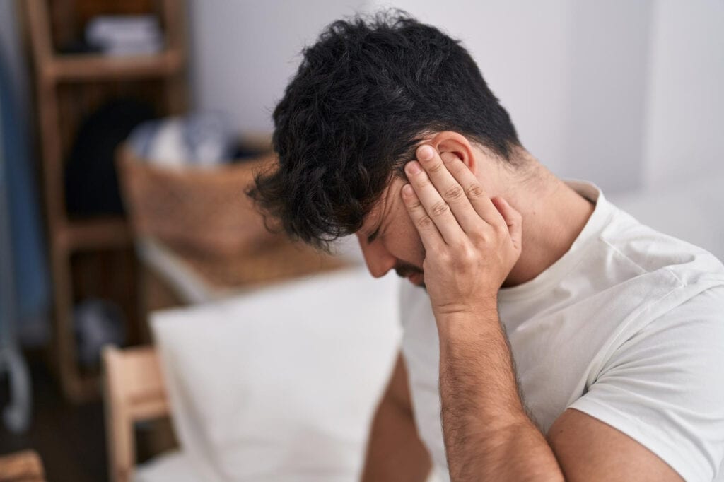 Man holding his ear with a pained expression, experiencing ear discomfort