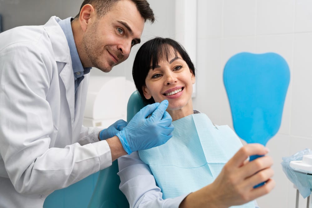 Dentist assisting a smiling female patient as she looks at her teeth