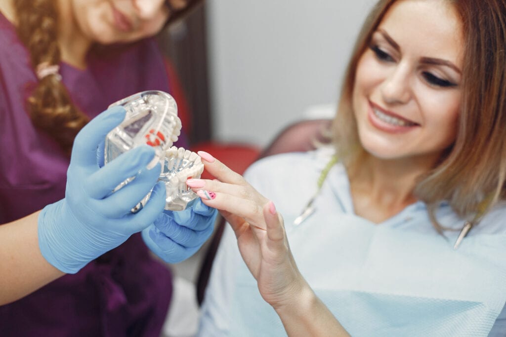 Dentist showing a patient a clear dental aligner and jaw model