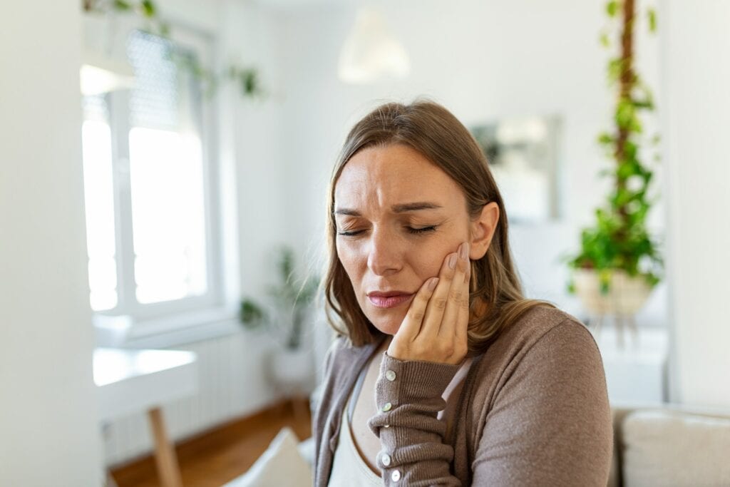 Woman with a pained expression resting her hand on her cheek
